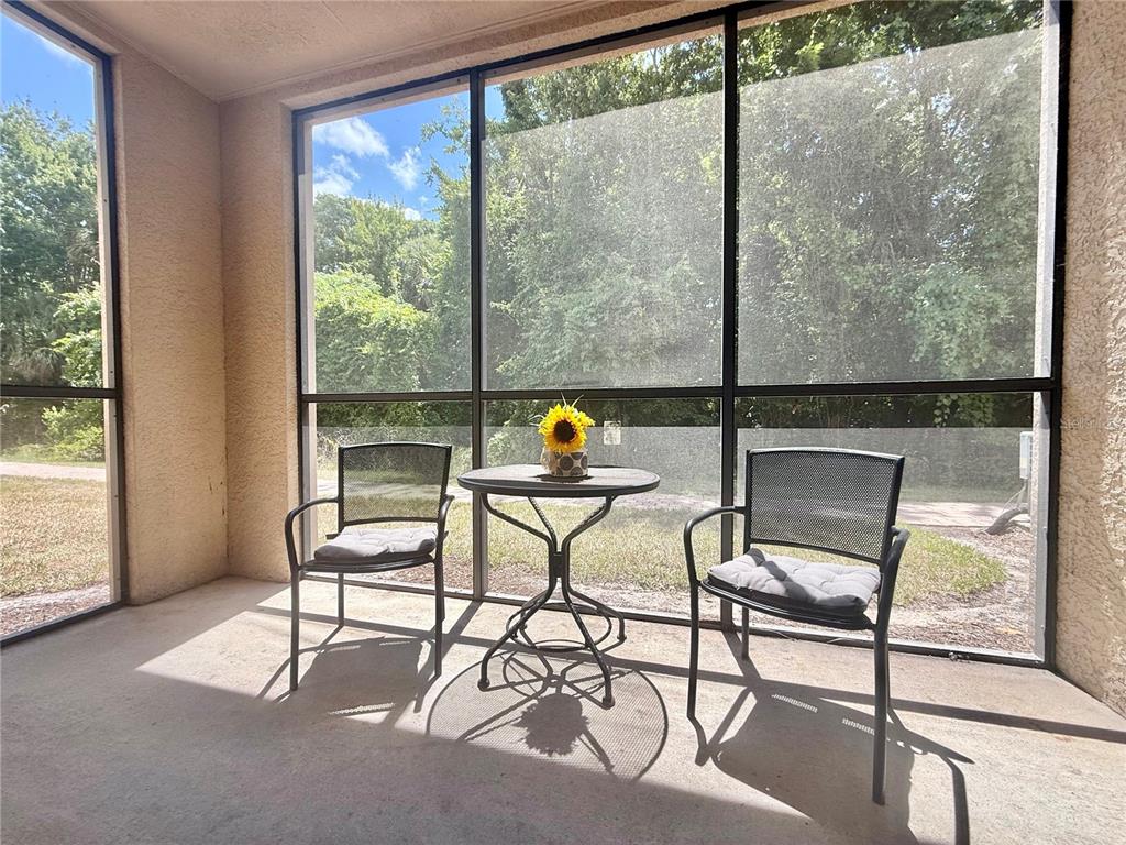 A screened-in porch features two metal chairs and a small table with a sunflower — 1301 TUSCAN TERRACE UNIT 9106, DAVENPORT, FL