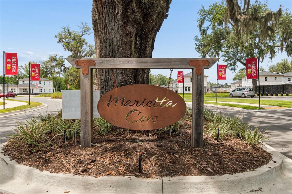 A rustic wooden sign for Marietta Cove stands in a landscaped traffic circle — 8268 MARIETTA STILL DRIVE, JACKSONVILLE, FL