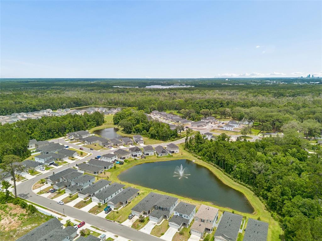 An aerial view of a suburban neighborhood featuring houses surrounding a central retention pond — 8268 MARIETTA STILL DRIVE, JACKSONVILLE, FL