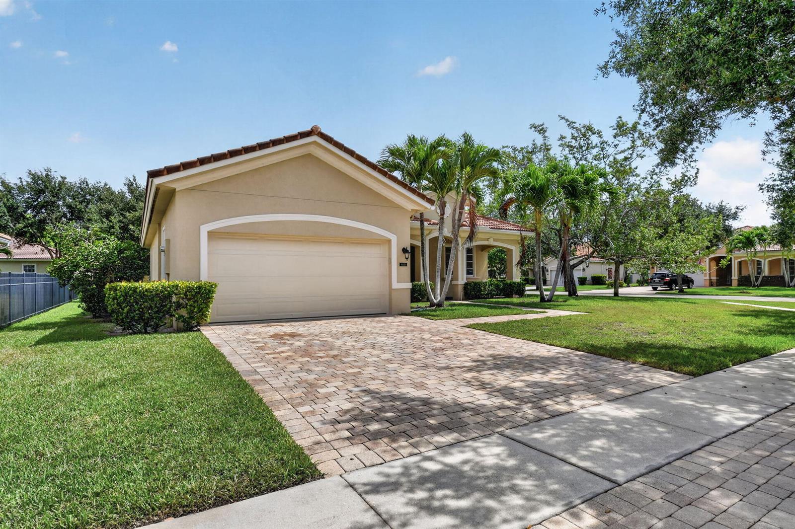 A single-story house with a beige stucco exterior, a tiled roof, and a paved driveway — 6810 Osage Circle, FL 33413, FL