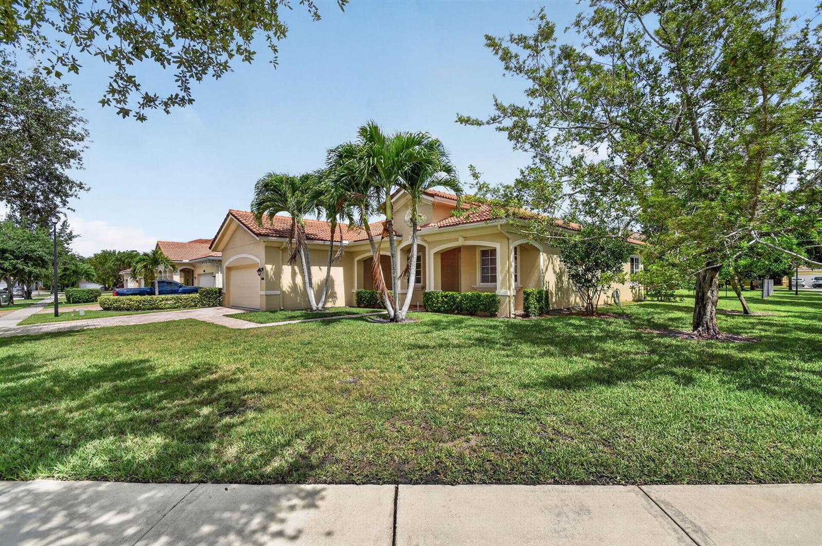 A single-story suburban house with a tile roof, palm trees, and a grassy front lawn — 6810 Osage Circle, FL 33413, FL