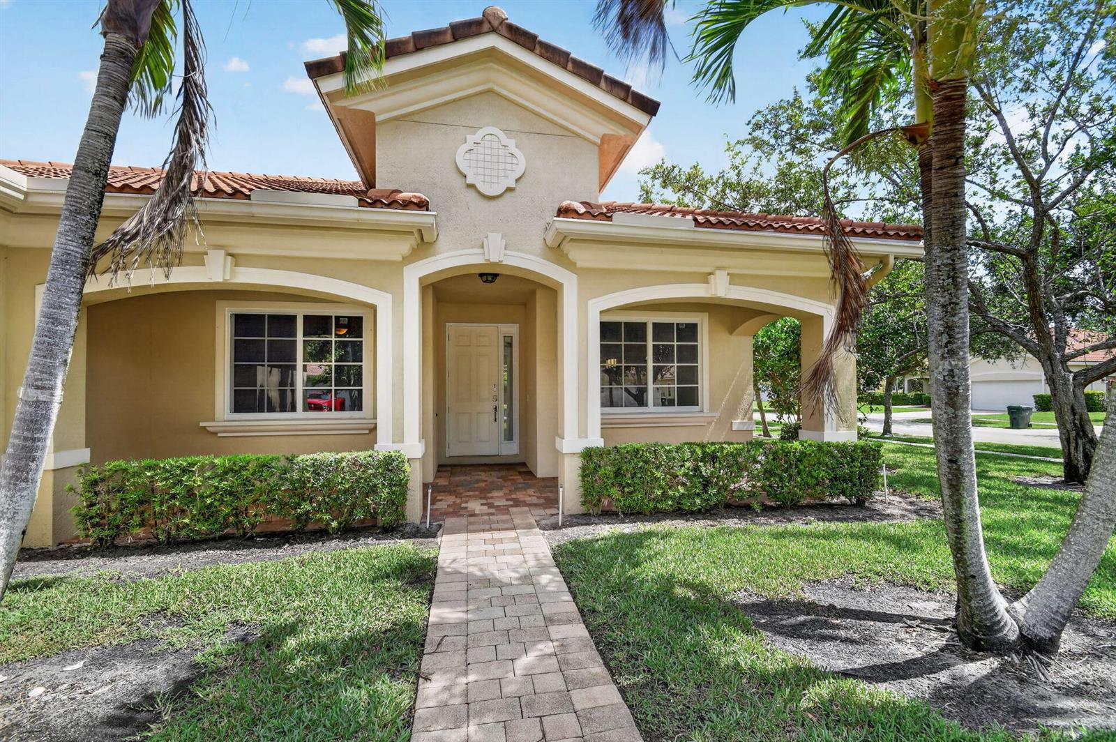 A single-story house with a beige stucco exterior, tile roof, and a brick walkway entrance — 6810 Osage Circle, FL 33413, FL