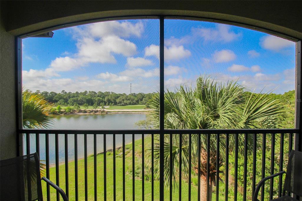 A screened-in balcony overlooks a lake, palm trees, and a golf course under a blue sky — 16706 VARDON TERRACE UNIT 405, BRADENTON, FL