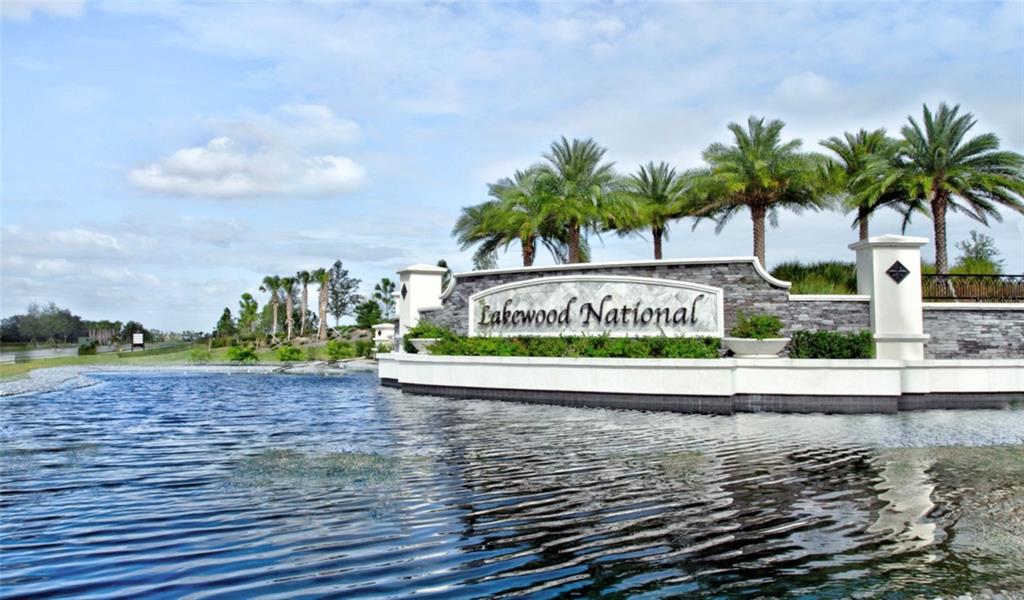 The entrance sign for Lakewood National stands behind a pond with palm trees in the background — 16706 VARDON TERRACE UNIT 405, BRADENTON, FL