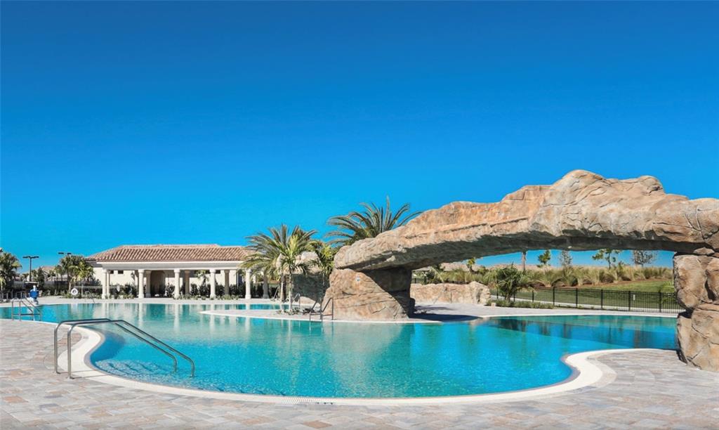 A swimming pool features a large artificial rock archway and a nearby clubhouse building — 16706 VARDON TERRACE UNIT 405, BRADENTON, FL