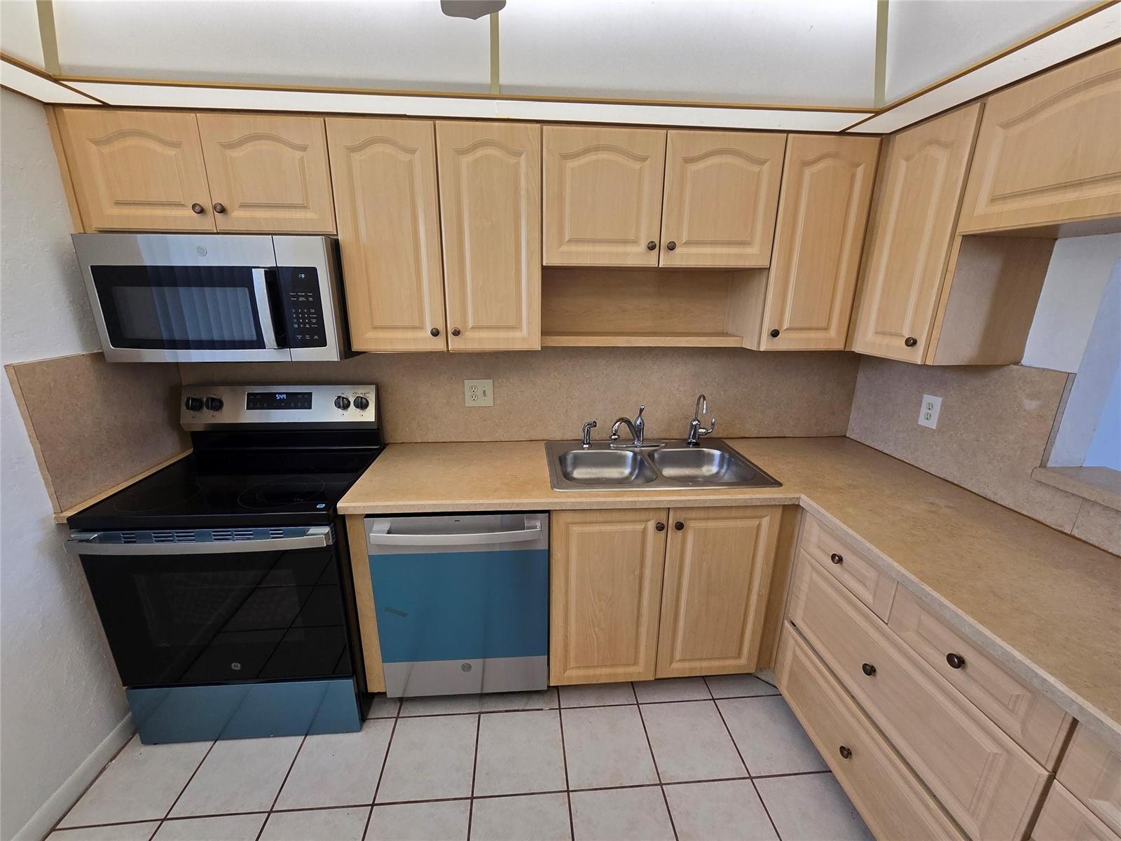 A kitchen features light wood cabinets, stainless steel appliances, and a double-basin sink — 6890 Royal Palm Boulevard # 211h, Margate FL 33063, MARGATE, FL