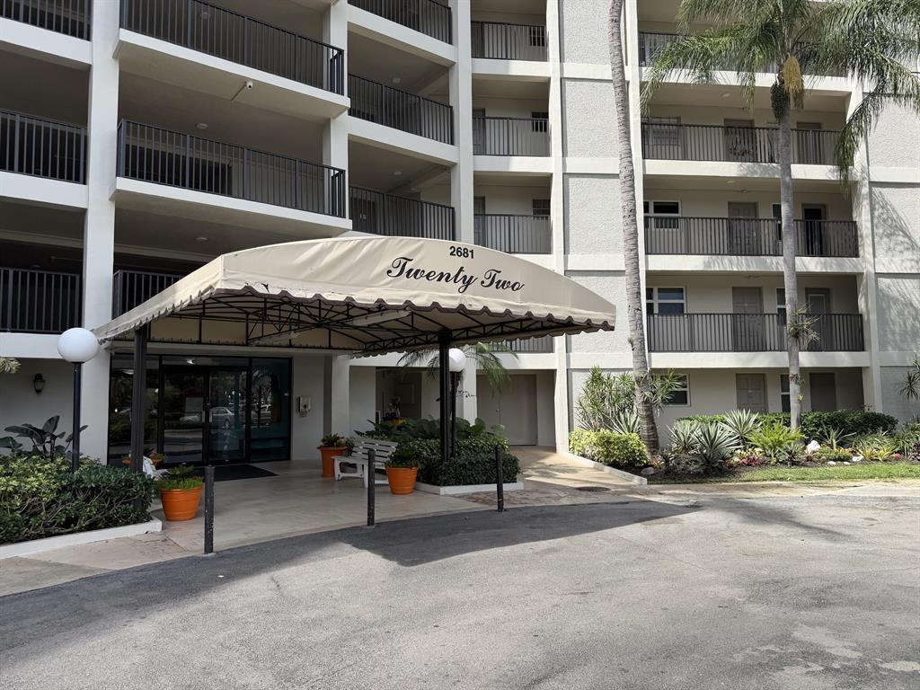 The exterior of a multi-story apartment building features a covered entrance with a beige awning — 2681 S Course Drive # 511, Pompano Beach FL 33069, POMPANO BEACH, FL