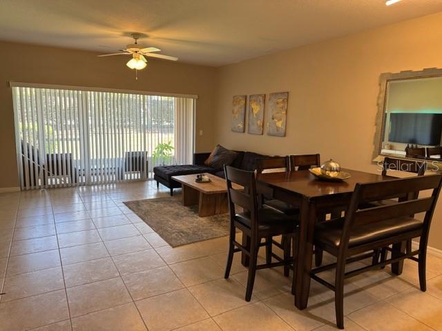 A dining area and living room feature tile flooring, a ceiling fan, and sliding glass doors — 222 BEXLEY DRIVE, DAVENPORT, FL