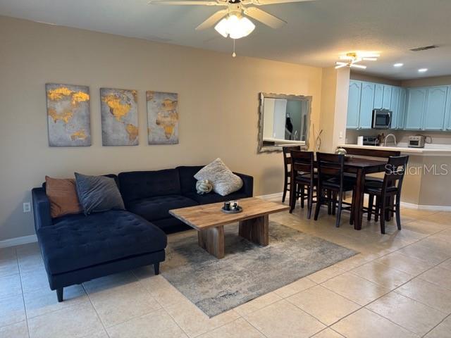 A living room with a dark sectional sofa, wood coffee table, and adjacent dining area — 222 BEXLEY DRIVE, DAVENPORT, FL