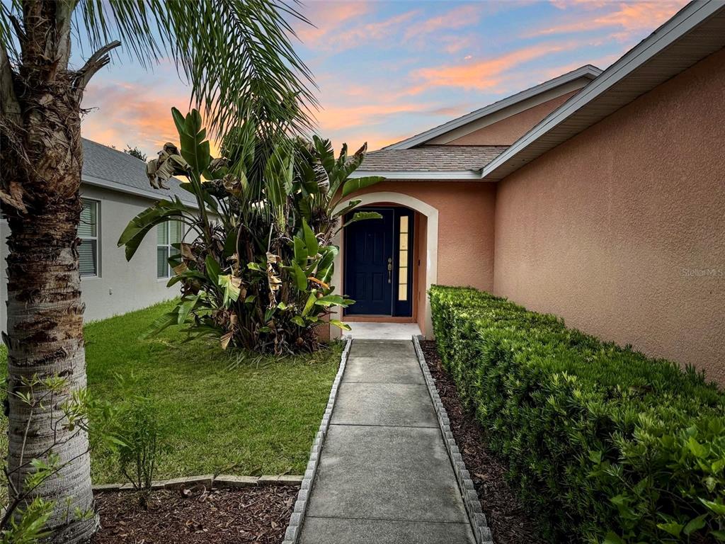 A concrete walkway leads to the dark blue front door of a peach-colored house — 7115 FOREST MERE DRIVE, RIVERVIEW, FL