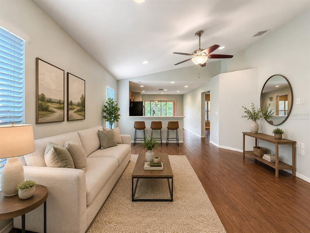 A living room features a beige sofa, wood coffee table, and a breakfast bar area — 7115 FOREST MERE DRIVE, RIVERVIEW, FL