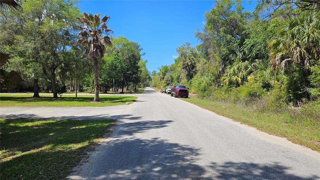 A paved road stretches through a wooded residential area with a parked red truck — 11201 W GEM STREET, CRYSTAL RIVER, FL