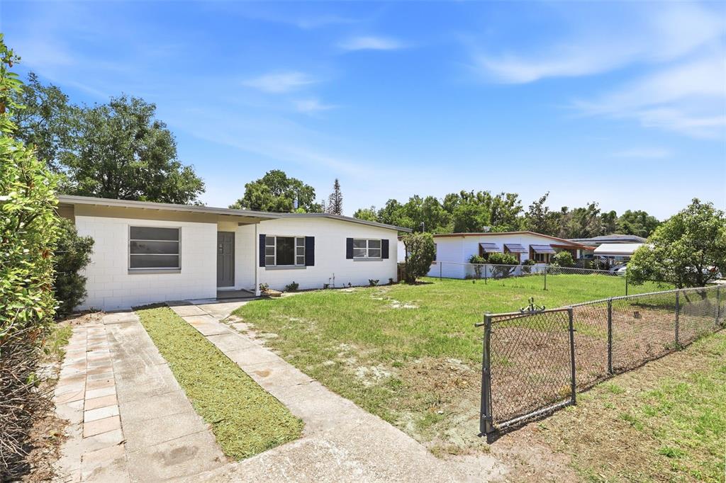 A white single-story house with a driveway and a chain-link fence in the front yard — 1300 MORNINGSIDE STREET, MOUNT DORA, FL