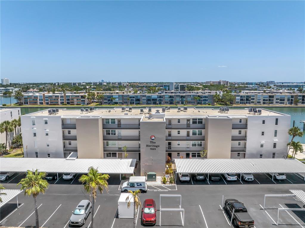 An aerial view shows a multi-story apartment building with covered parking and a nearby canal — 7625 SUN ISLAND DRIVE S UNIT 106, SOUTH PASADENA, FL