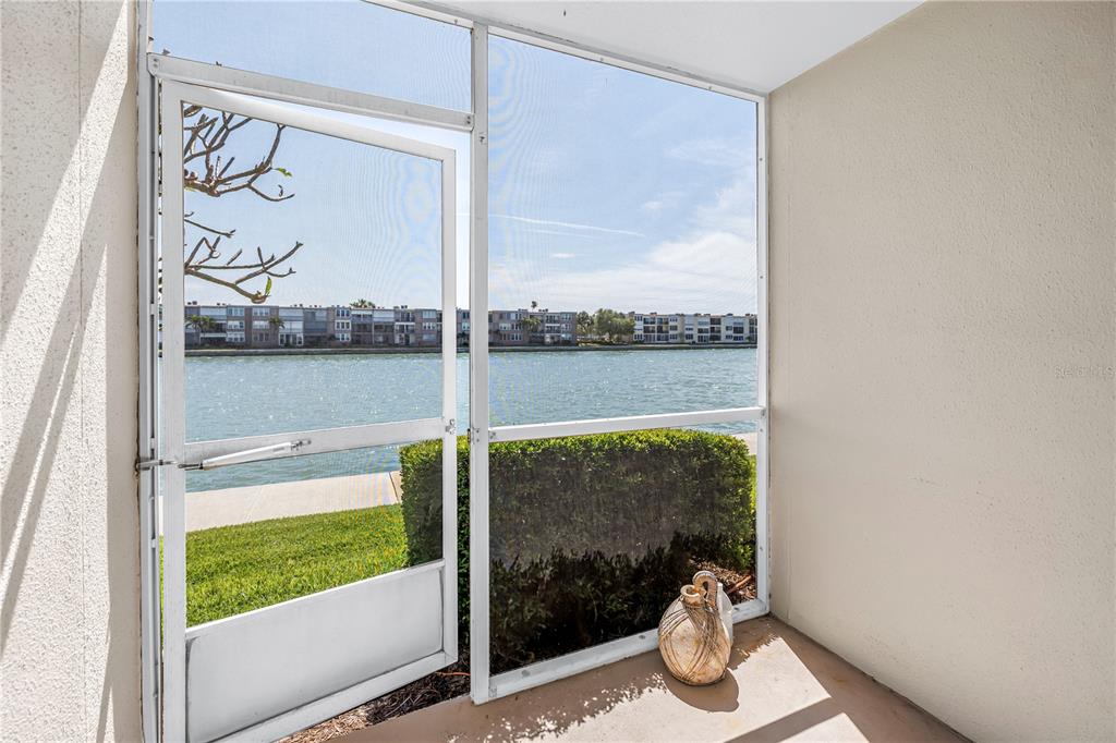 A screened-in porch overlooks a canal with apartment buildings in the background — 7625 SUN ISLAND DRIVE S UNIT 106, SOUTH PASADENA, FL