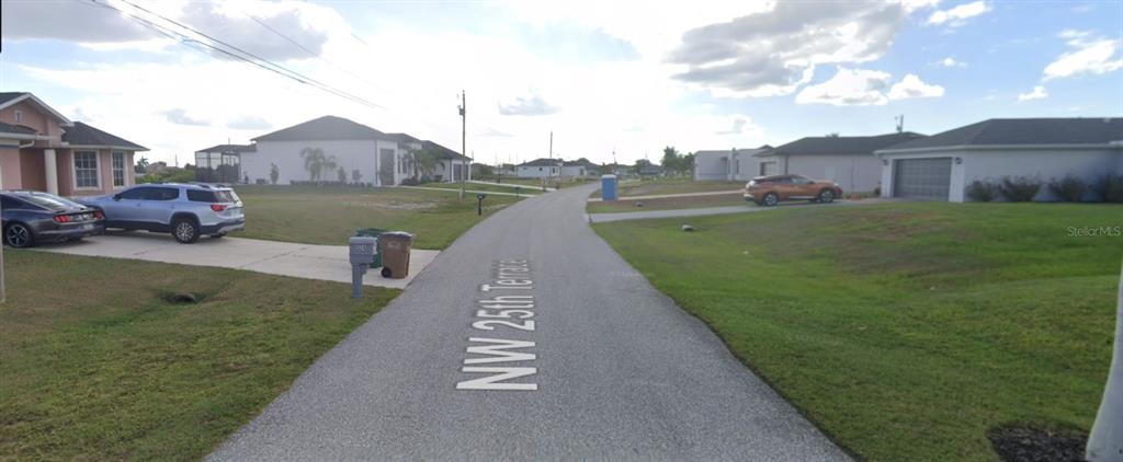 A street view shows a paved road with houses on both sides under a cloudy sky — 520 NW 25TH TERRACE, CAPE CORAL, FL