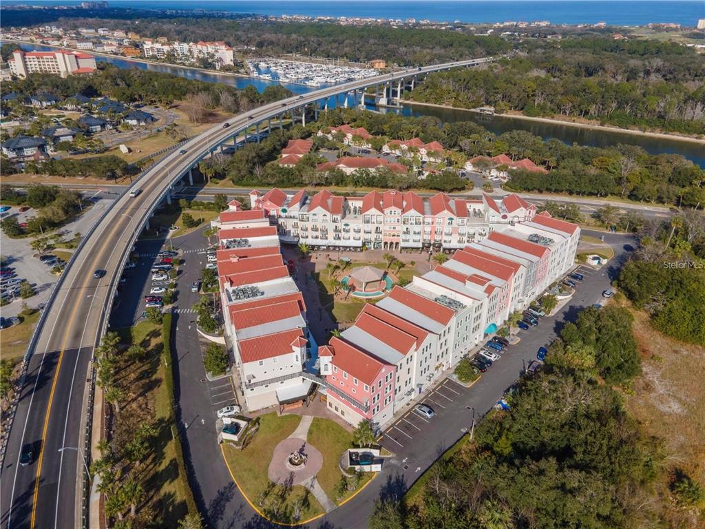 An aerial view shows a multi-story residential complex with red roofs near a bridge — 101 PALM HARBOR PARKWAY UNIT A305, PALM COAST, FL