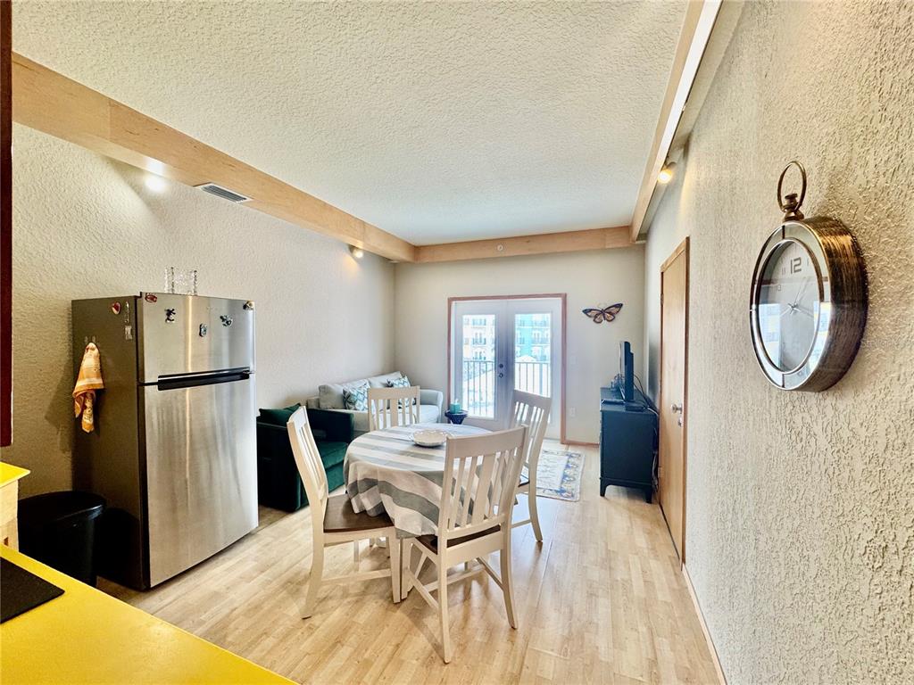 A dining area with a round table and chairs sits next to a stainless refrigerator — 101 PALM HARBOR PARKWAY UNIT A305, PALM COAST, FL