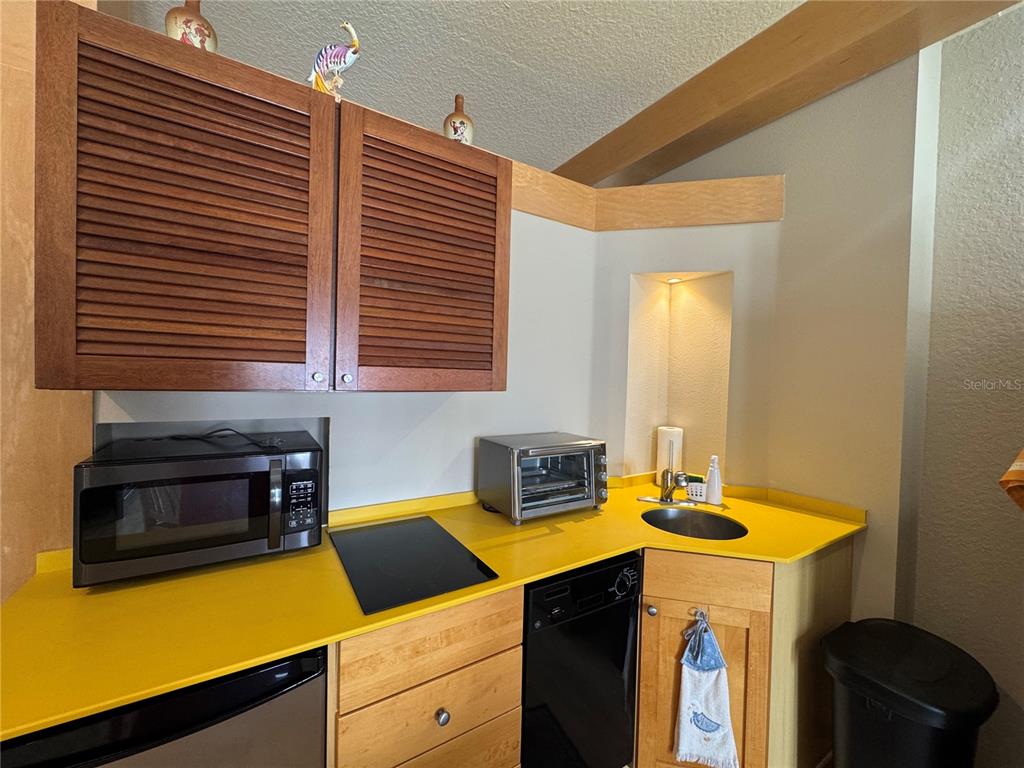 A small kitchen features yellow countertops, wooden cabinets, a microwave, and a toaster oven — 101 PALM HARBOR PARKWAY UNIT A305, PALM COAST, FL