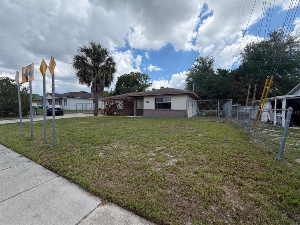 A single-story house with a brick and stucco exterior sits behind a chain-link fence — 1057 FORT SMITH BOULEVARD, DELTONA, FL