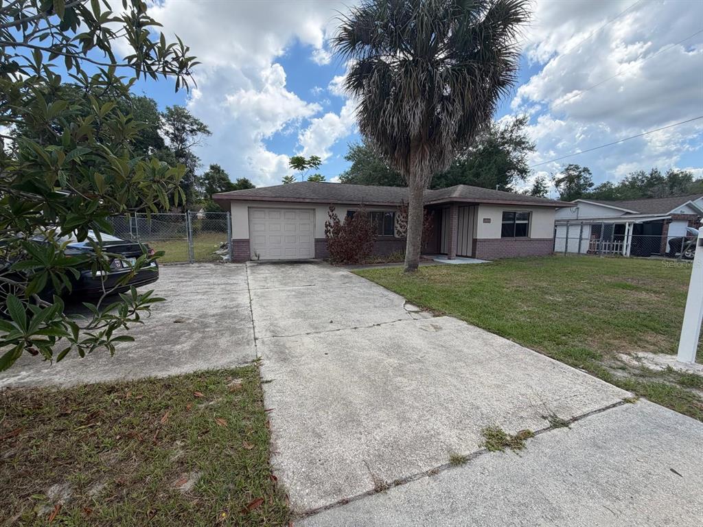 A single-story house with a concrete driveway, a garage, and a large palm tree — 1057 FORT SMITH BOULEVARD, DELTONA, FL