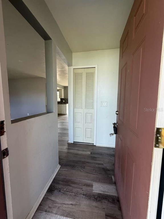 An entryway with wood-look flooring, a closet with louvered doors, and a partial wall cutout — 1057 FORT SMITH BOULEVARD, DELTONA, FL