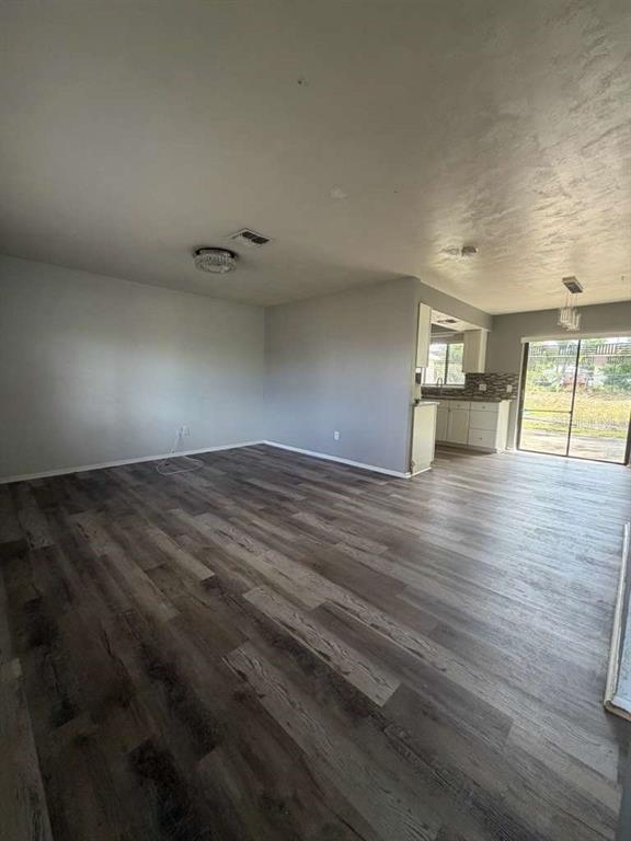 An open-concept living and dining area features gray walls and wood-look plank flooring — 1057 FORT SMITH BOULEVARD, DELTONA, FL