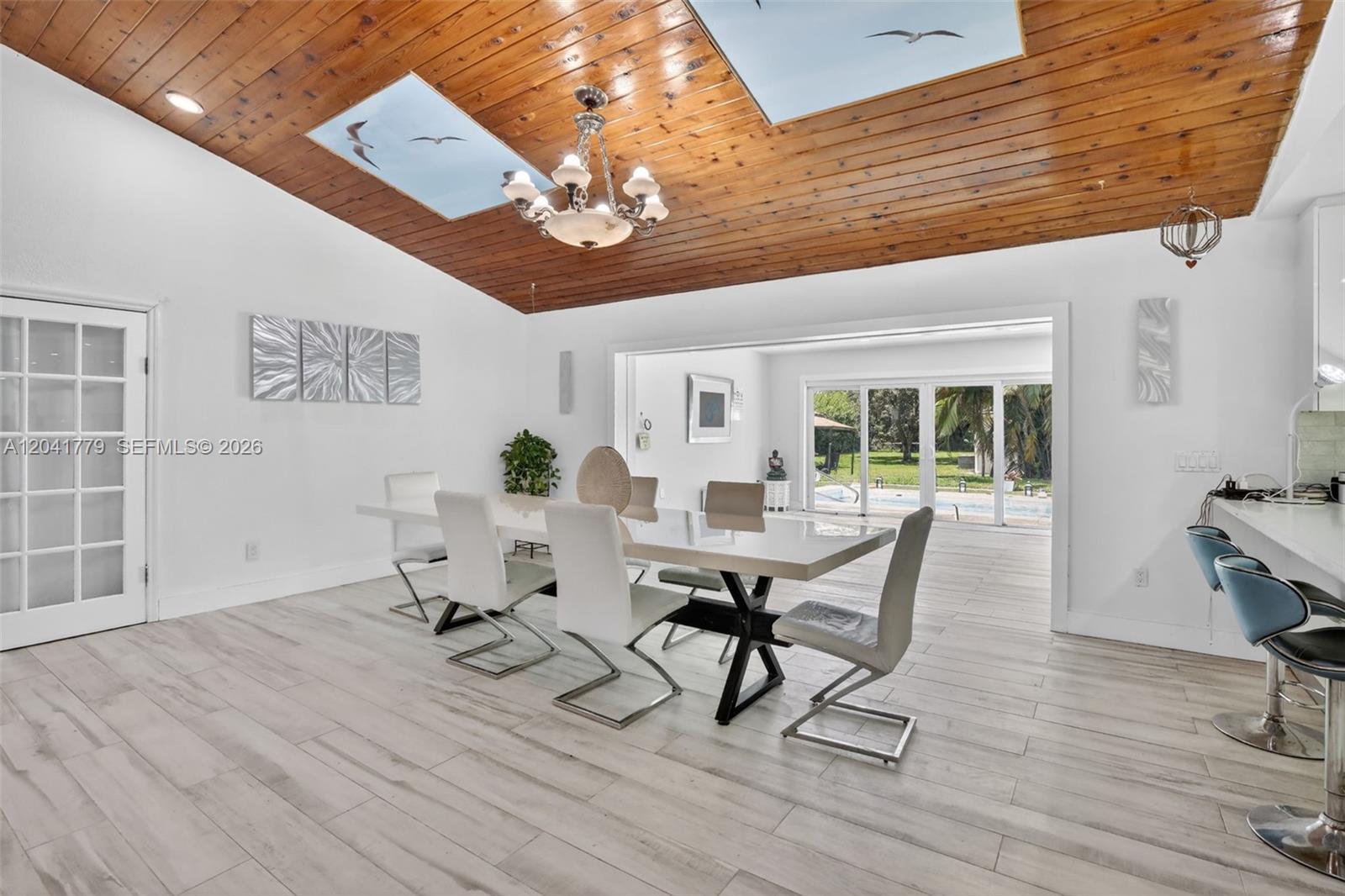 A dining room features a wood-paneled vaulted ceiling with skylights and a view outdoors — DAVIE, FL