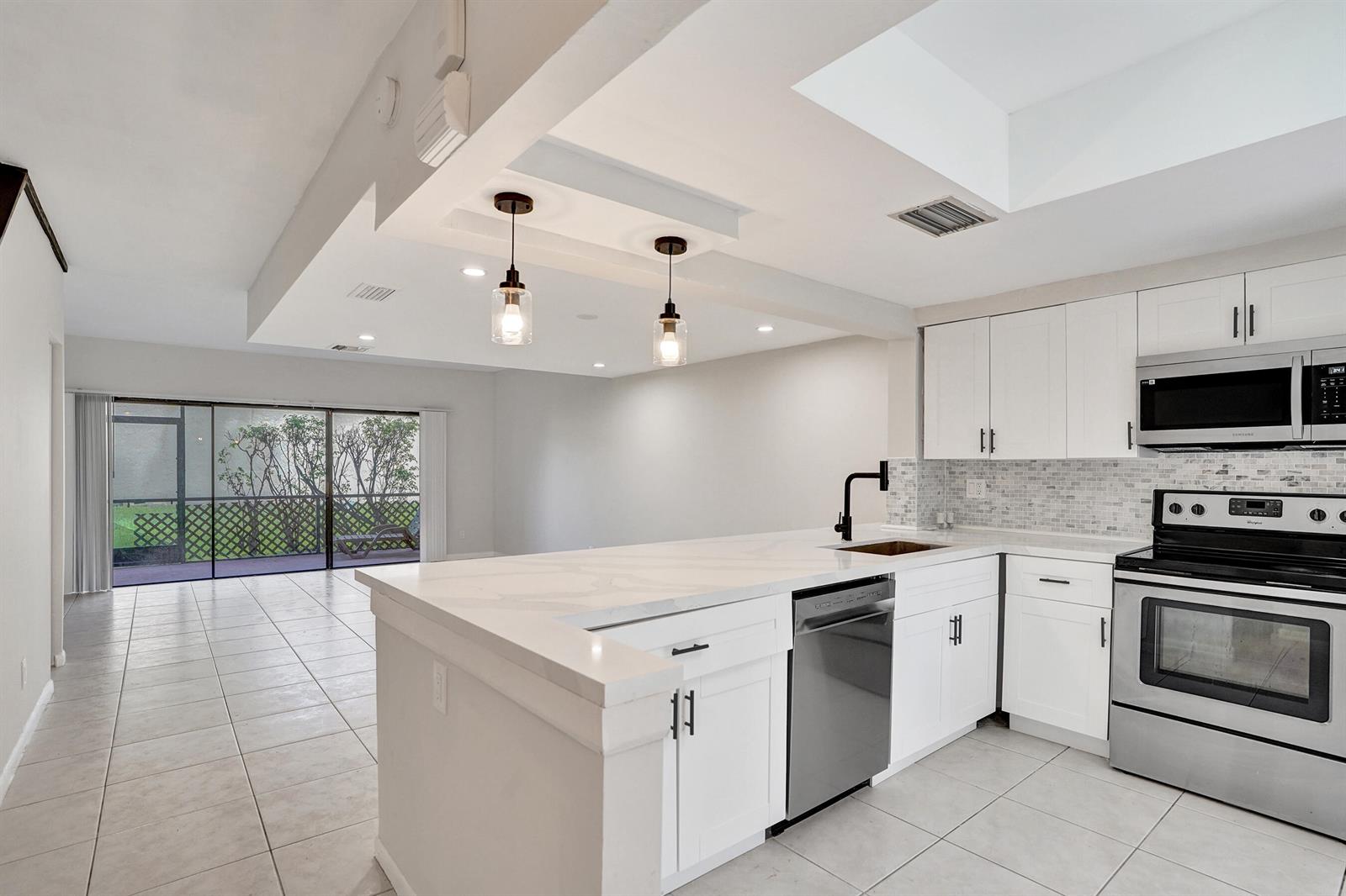 A modern kitchen features white cabinets, quartz countertops, stainless steel appliances, and a breakfast bar — 4732 NW 90th Avenue # 4732, Sunrise FL 33351, SUNRISE, FL