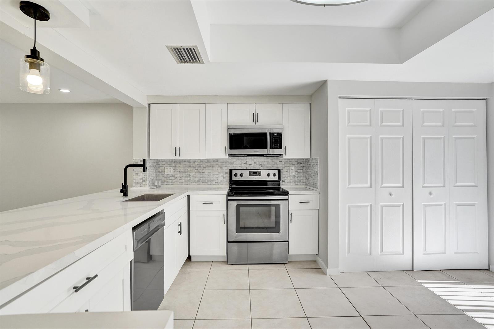 A kitchen features white cabinets, stainless steel appliances, a tiled backsplash, and a quartz countertop — 4732 NW 90th Avenue # 4732, Sunrise FL 33351, SUNRISE, FL