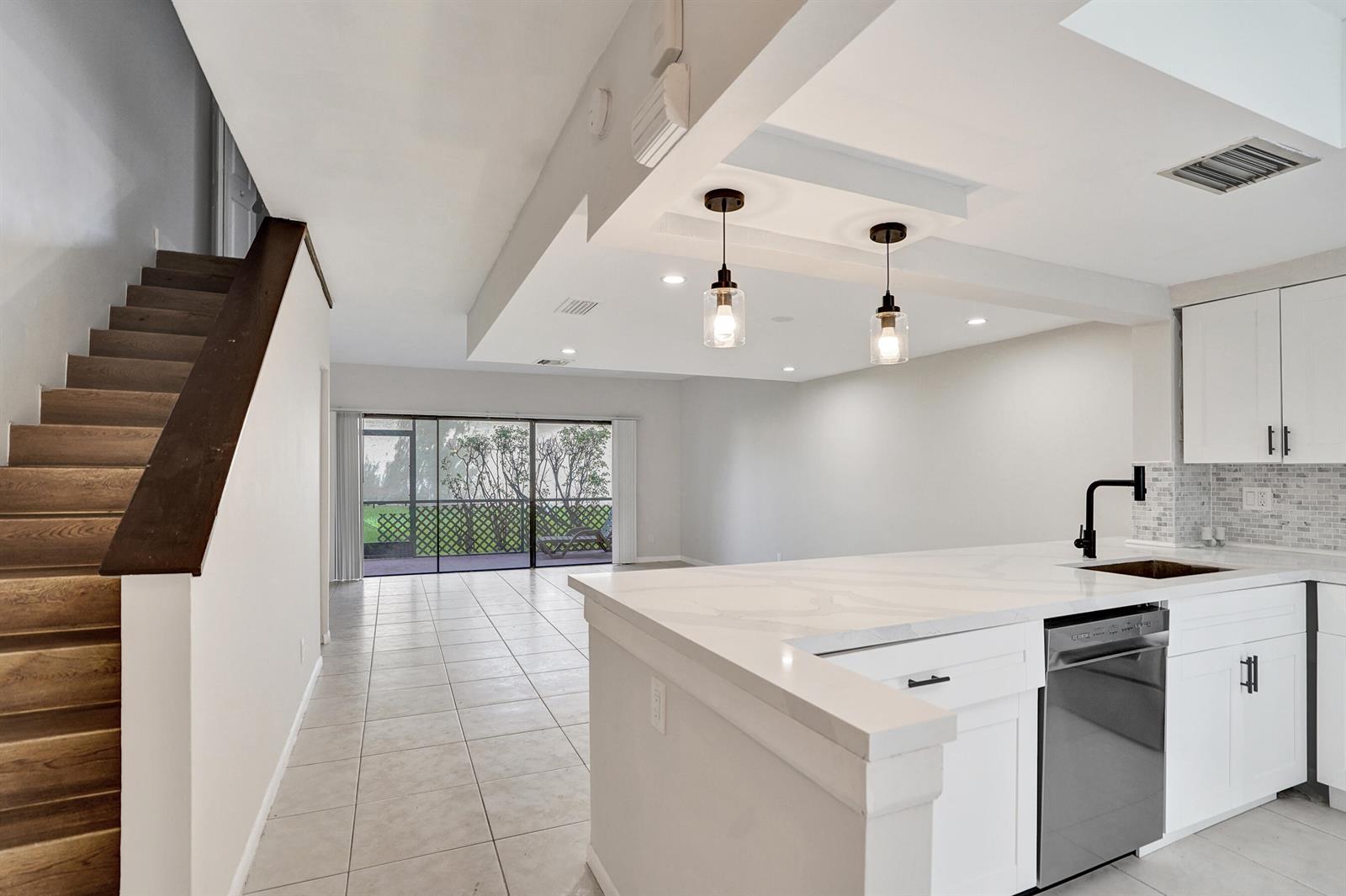 A kitchen with white cabinets and a quartz island overlooks a tiled living area — 4732 NW 90th Avenue # 4732, Sunrise FL 33351, SUNRISE, FL