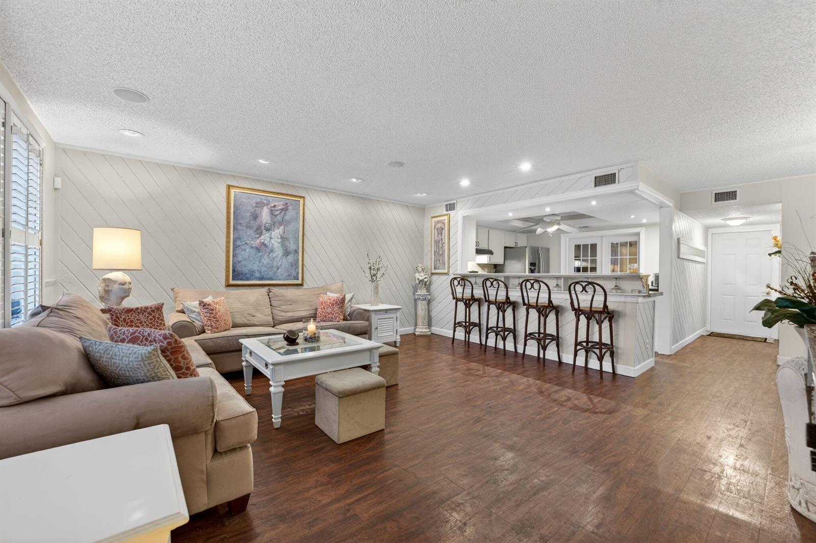 A living room with wood-look flooring, a sectional sofa, and a breakfast bar with stools — 3951 NE 17th Avenue # 703, Pompano Beach FL 33064, POMPANO BEACH, FL