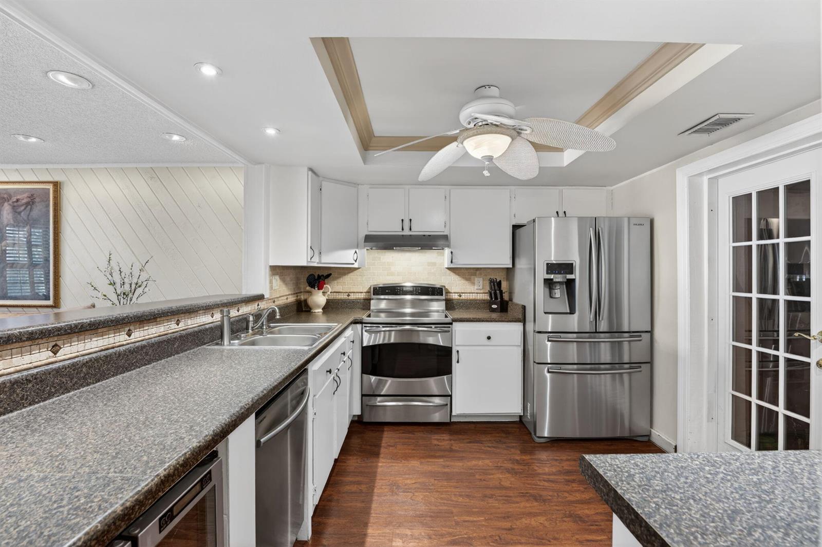 A kitchen features white cabinets, stainless steel appliances, dark countertops, and wood-look flooring — 3951 NE 17th Avenue # 703, Pompano Beach FL 33064, POMPANO BEACH, FL
