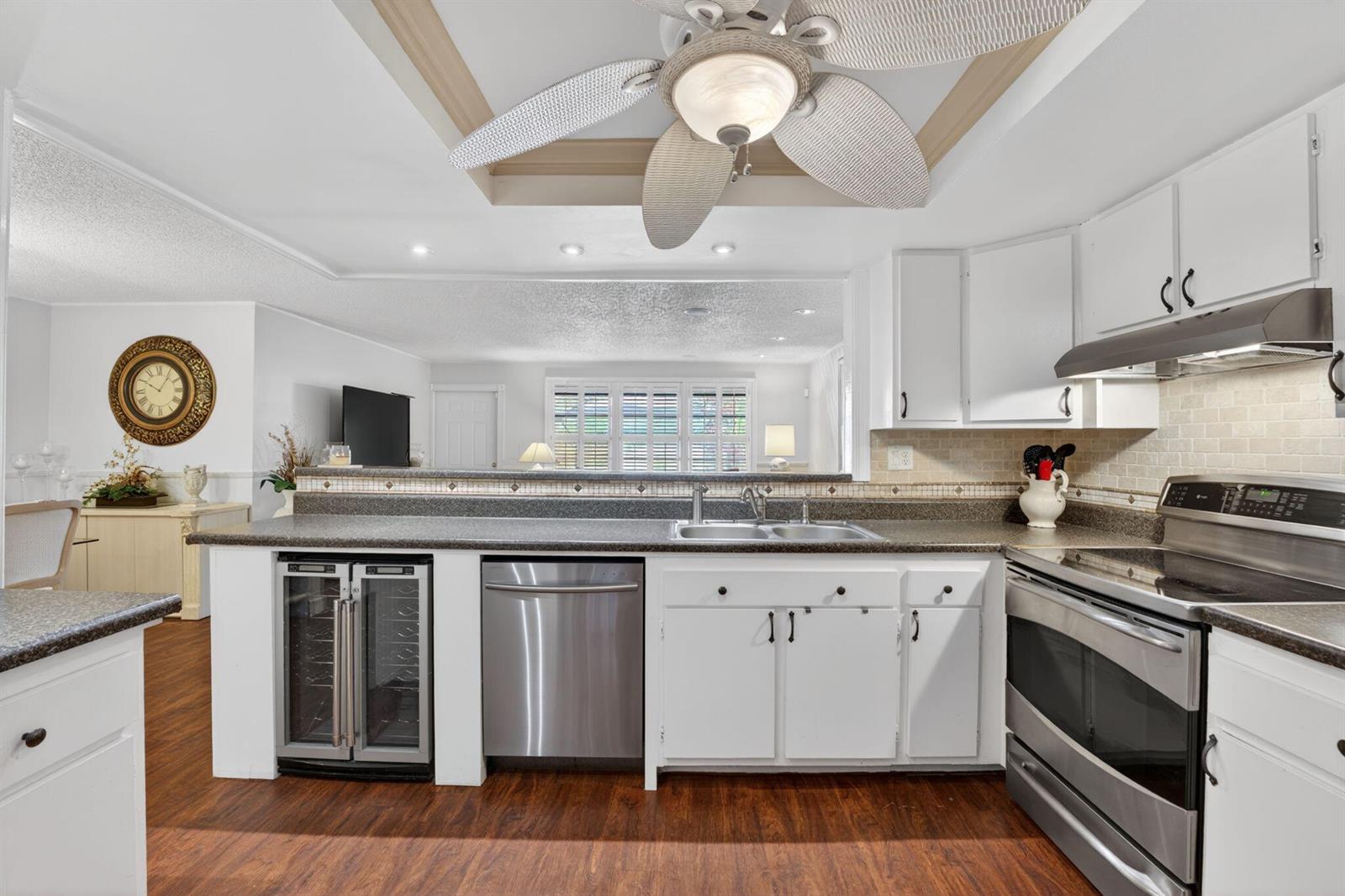 A kitchen features white cabinetry, stainless steel appliances, a wine cooler, and a ceiling fan — 3951 NE 17th Avenue # 703, Pompano Beach FL 33064, POMPANO BEACH, FL