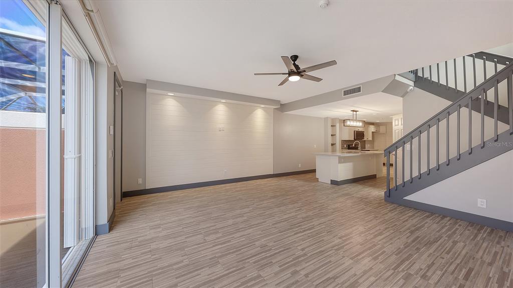 An open-concept living area features wood-look flooring, a shiplap accent wall, and a staircase — 1586 DORGALI DRIVE, SARASOTA, FL