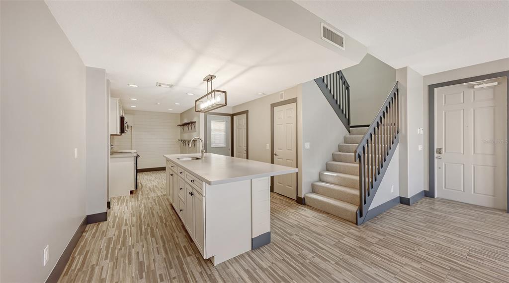 A kitchen with a central island, light-colored cabinetry, and stairs leading to an upper level — 1586 DORGALI DRIVE, SARASOTA, FL