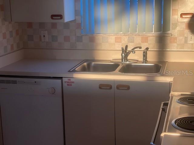 A kitchen features a double-basin sink, white cabinets, a dishwasher, and a tiled backsplash — 901 OCEAN MARINA DRIVE UNIT 901, FLAGLER BEACH, FL