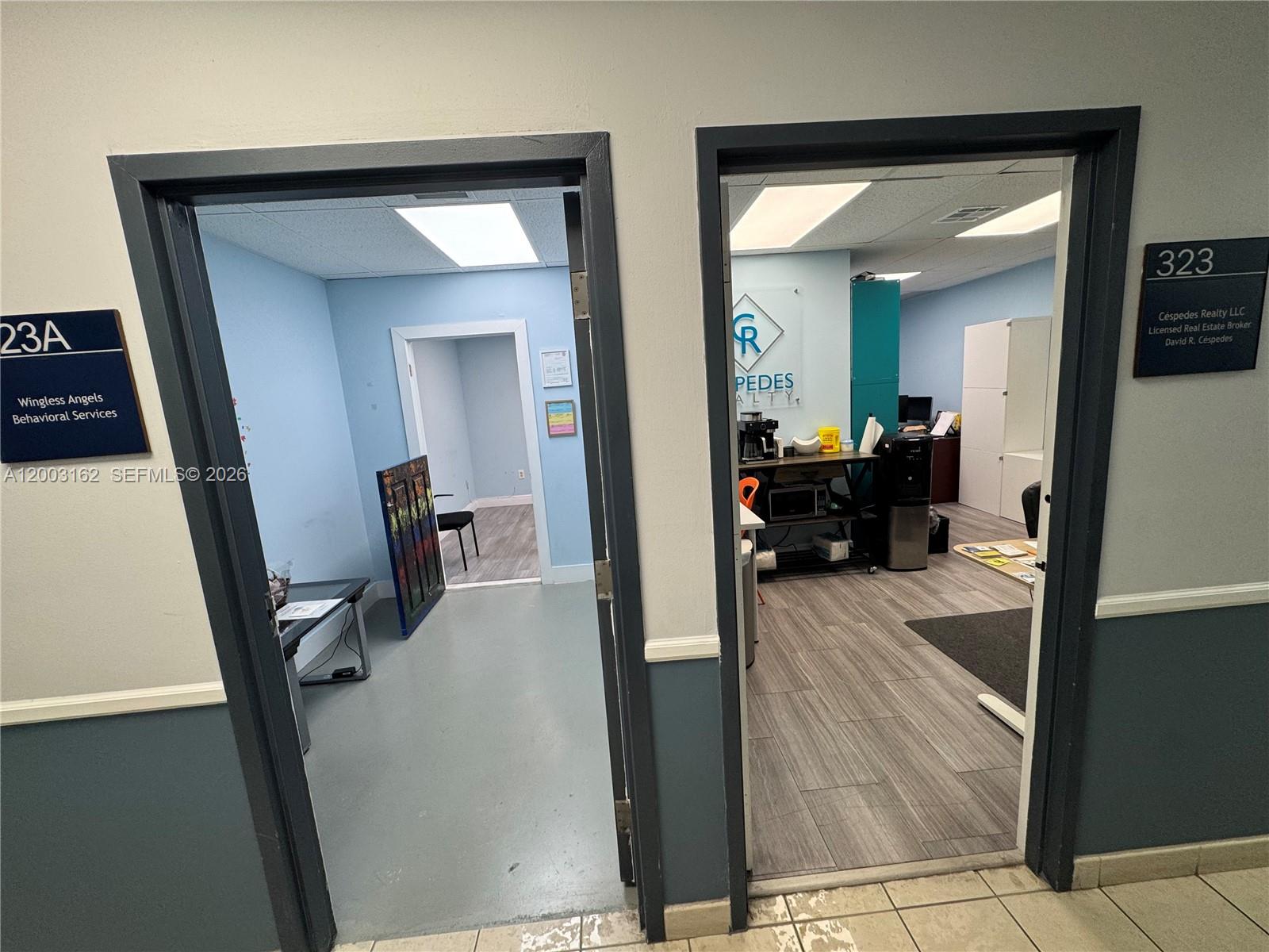 Two office suites with gray-painted walls, wood-look flooring, and signage for two different businesses — 717 Ponce De Leon Blvd # 323, Coral Gables FL 33134, CORAL GABLES, FL