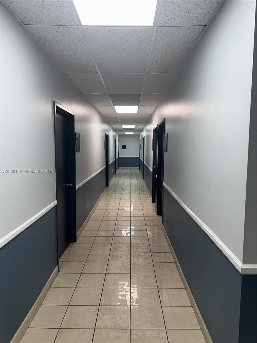 A long, narrow hallway features tiled flooring, dark doors, and two-toned gray walls — 717 Ponce De Leon Blvd # 323, Coral Gables FL 33134, CORAL GABLES, FL