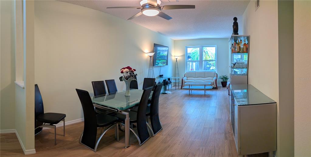 A dining area with a glass table and chairs opens into a living room space — 2983 COVEWOOD PLACE, CLEARWATER, FL