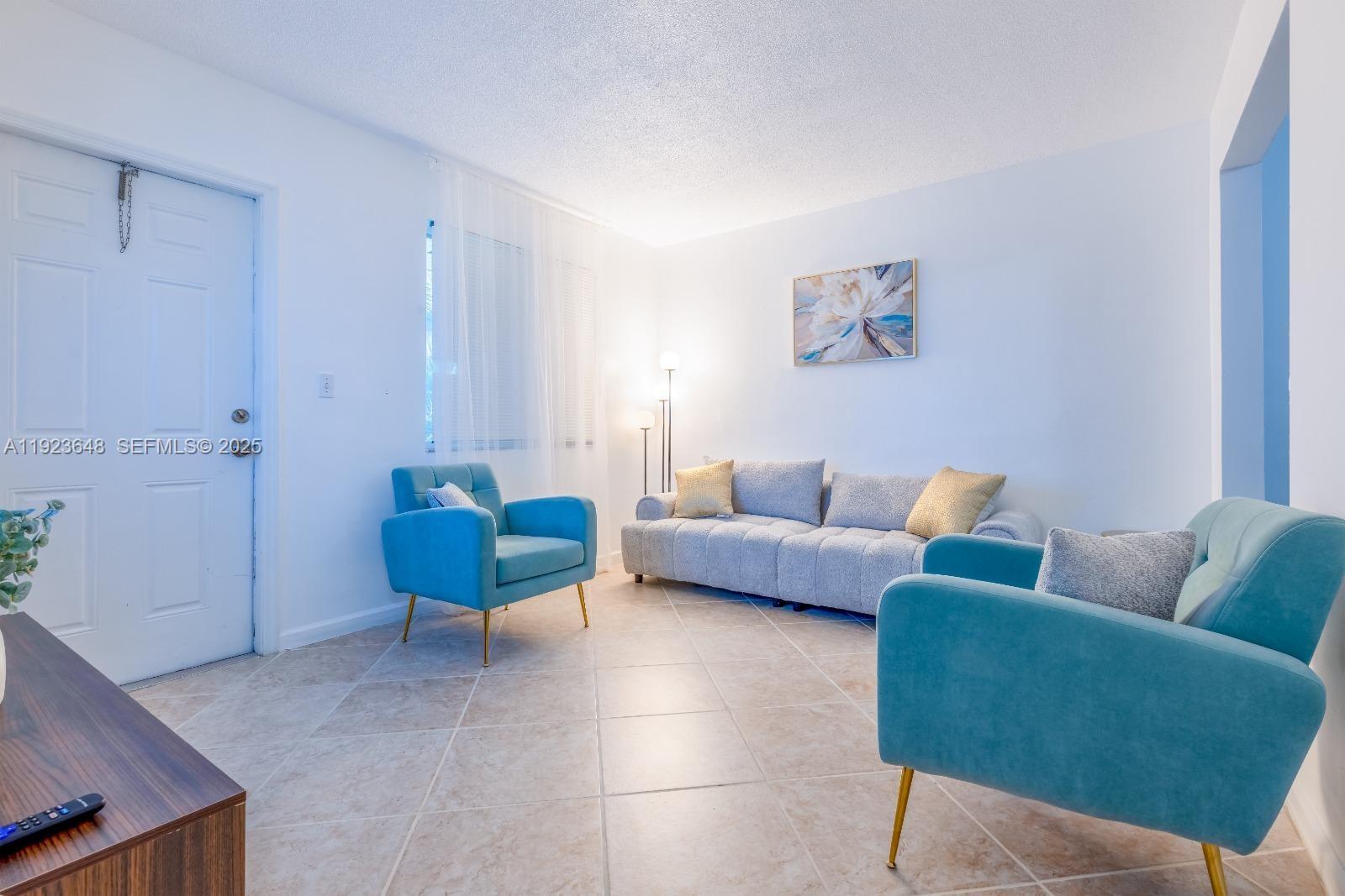 A living room features a gray sofa, two teal armchairs, and light-colored tile flooring — 828 SW 2nd St # 2, Miami FL 33130, MIAMI, FL