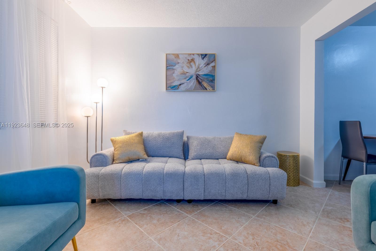 A living room features a gray tufted sofa, gold accent pillows, and a floor lamp — 828 SW 2nd St # 2, Miami FL 33130, MIAMI, FL