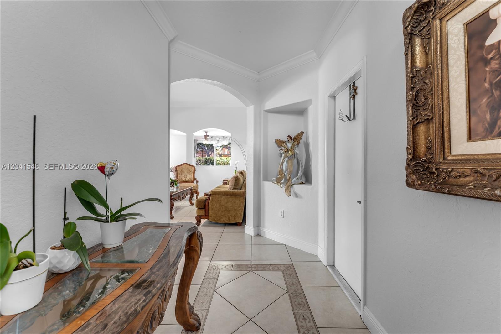 A tiled hallway leads to a living area featuring an arched entryway and wall niche — 15506 SW 25th Ter, Miami FL 33185, MIAMI, FL