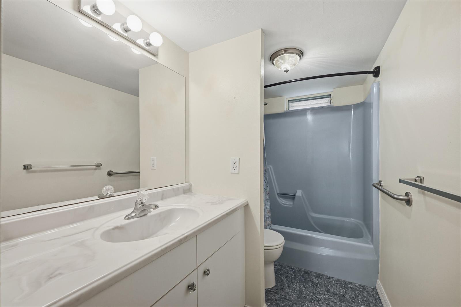 A bathroom features a white vanity, a large mirror, and a blue tub-shower combination — 130 NE 26th Avenue # 4090, Boynton Beach FL 33435, BOYNTON BEACH, FL