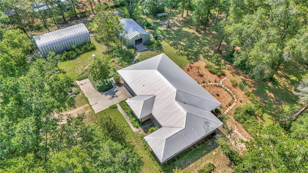An aerial view shows a house with a metal roof, two outbuildings, and surrounding trees — 17690 SE 66 PLACE, MORRISTON, FL