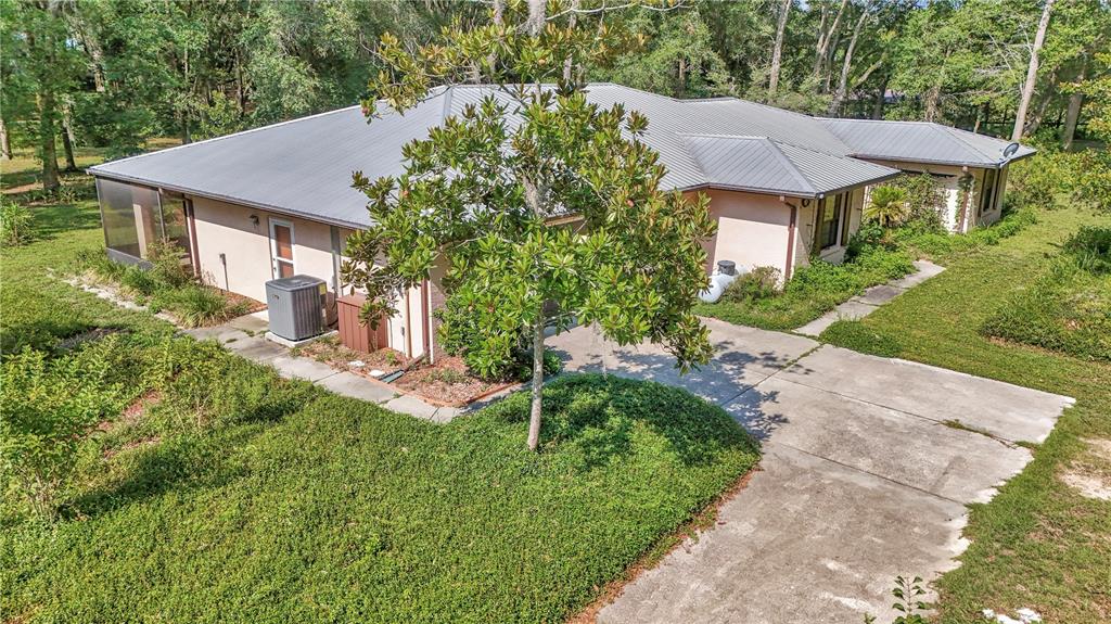 An aerial view of a single-story house with a metal roof and a concrete driveway — 17690 SE 66 PLACE, MORRISTON, FL