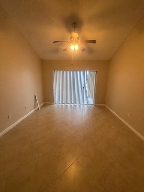 An empty room with beige tile flooring, a ceiling fan, and vertical blinds on sliding doors — 2640 S University Drive # 305, Davie FL 33328, DAVIE, FL
