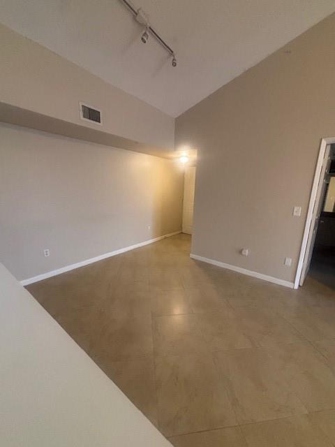 An empty room with beige walls, tile flooring, and track lighting on a vaulted ceiling — 2640 S University Drive # 305, Davie FL 33328, DAVIE, FL