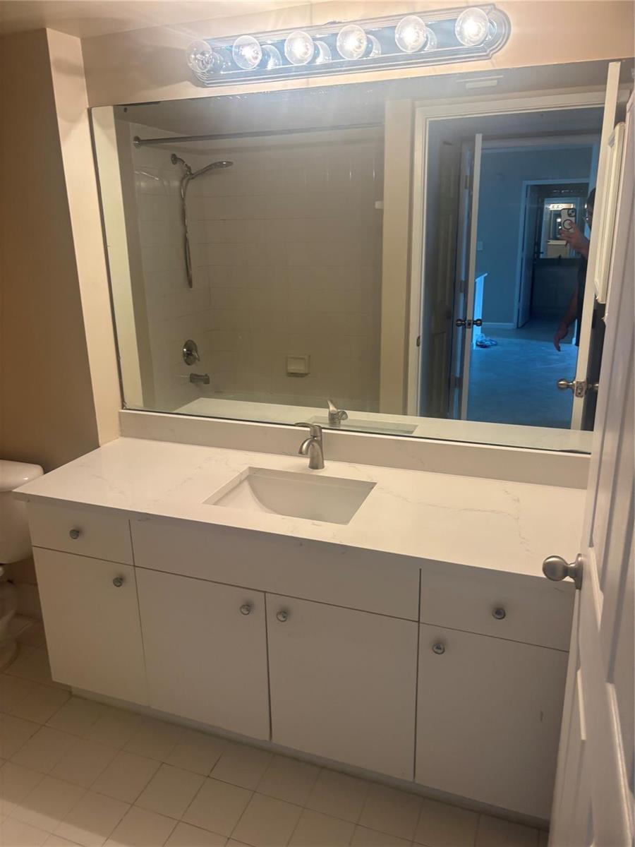 A bathroom features a white vanity with a quartz countertop, a large mirror, and lighting — 2640 S University Drive # 305, Davie FL 33328, DAVIE, FL