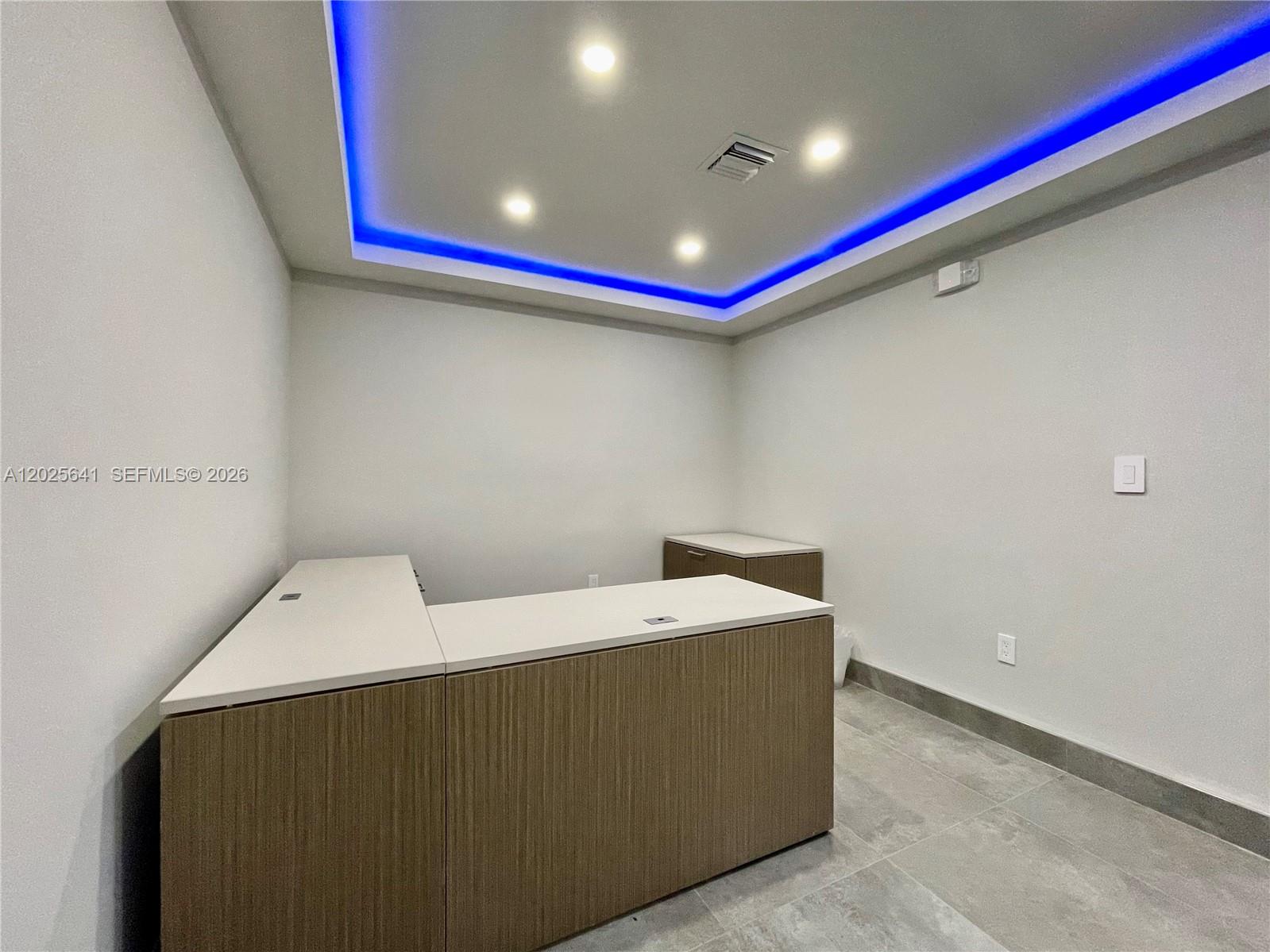 An office room features a built-in desk, tile flooring, and a tray ceiling with blue lighting — 6280 W Atlantic Blvd, Margate FL 33063, MARGATE, FL